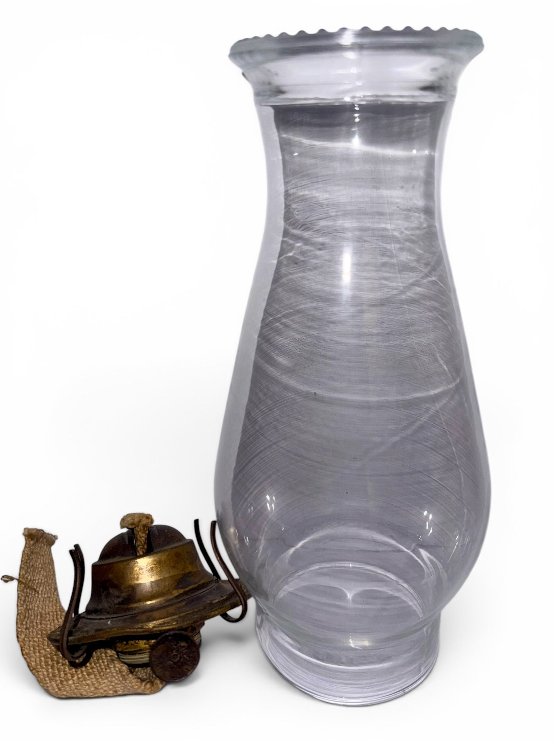 Clear glass hurricane lamp with a brass lantern on a white background