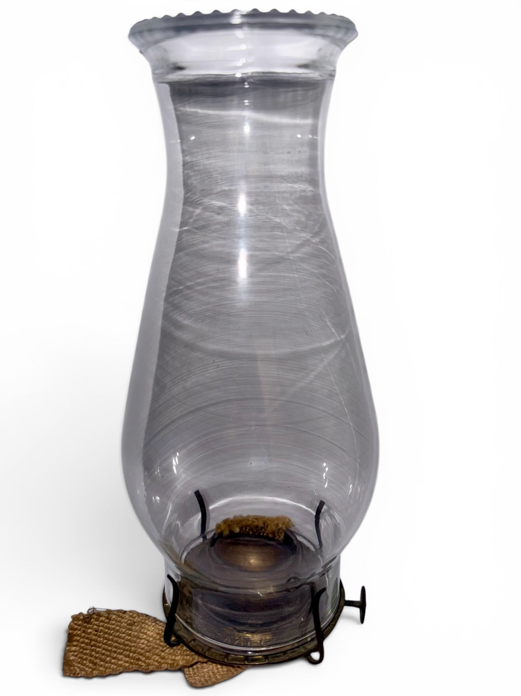 Clear glass oil lamp chimney with a brass burner against a white background